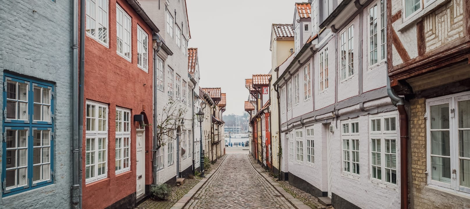 Blick durch den Oluf-Samson-Gang in Flensburg mit kleine Altbauten mit bunten Fassaden und weißen Sprossenfenstern